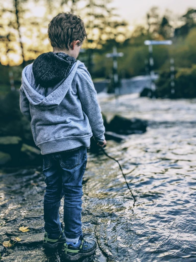 a boy with a stick looking very sad