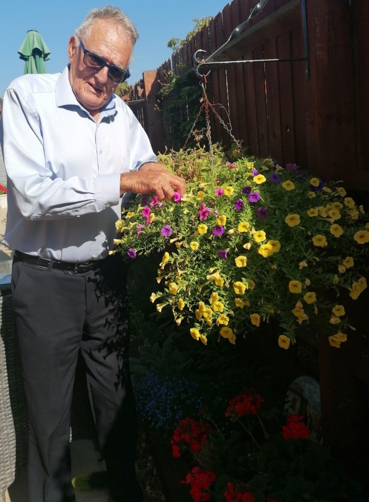 Dennis tends to some yellow plants in hanging baskets in Love Your Garden