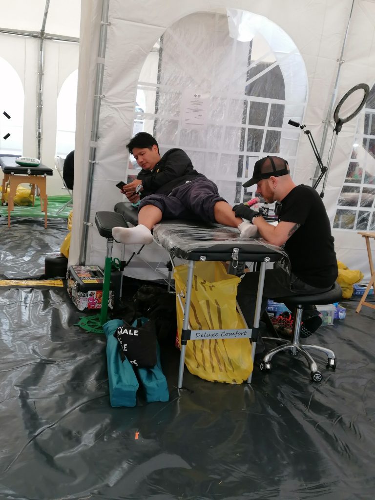 A tattooist works on someone's leg.