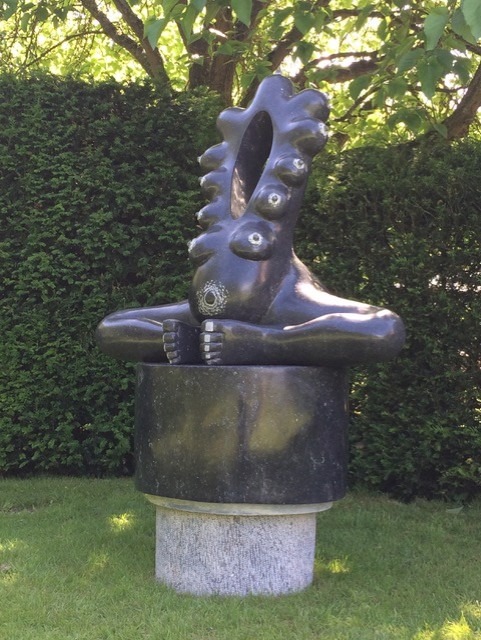 A stone carving of a woman with multiple breasts. 