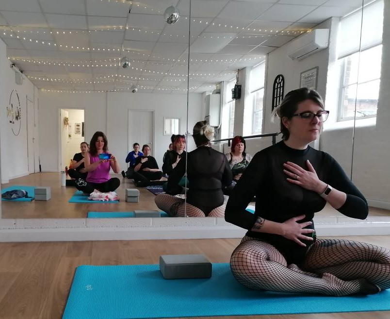 A yoga teacher places hand on chest. 