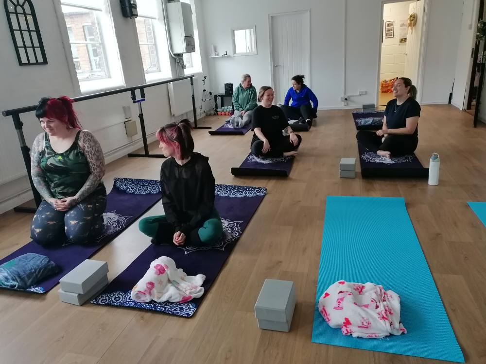 Seven ladies on yoga mats on the floor. 