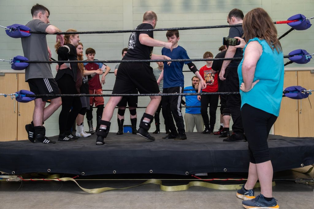 Lots of people gather in a wrestling ring. 