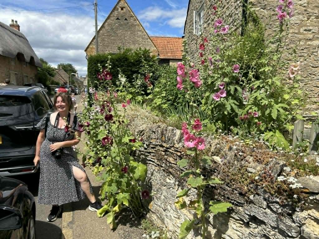 a lady next to a cottage agrden